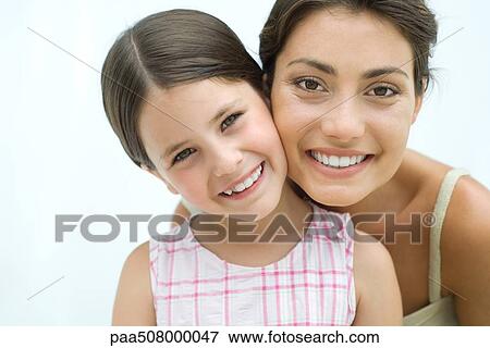Stock Photo - Mother and daughter cheek to cheek, both smiling at camera. Fotosearch