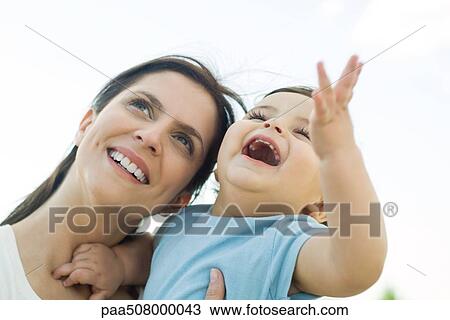 Mother holding baby, both looking up and smiling View Large Photo Image Stock Image - Mother holding baby, both looking up and smiling. Fotosearch