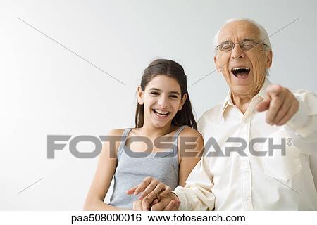 Teenage girl side by side with grandfather, both laughing, senior man pointing at camera View Large Photo Image Stock Photograph - Teenage girl side by side with grandfather, both laughing, senior man pointing at camera. Fotosearch