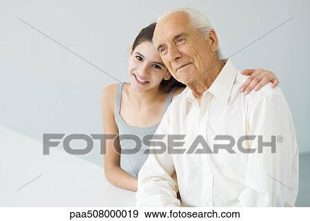 Teenage girl with arm around her grandfather's shoulder, senior man looking away View Large Photo Image Stock Photo - Teenage girl with arm around her grandfather's shoulder, senior man looking away. Fotosearch