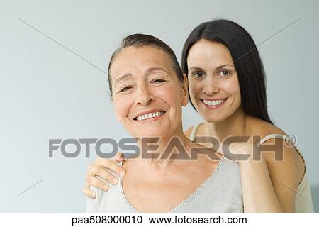 Woman behind senior mother, hands on shoulders, both smiling at camera, portrait View Large Photo Image Stock Image - Woman behind senior mother, hands on shoulders, both smiling at camera, portrait. Fotosearch