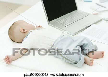 Infant sleeping on desk beside laptop computer View Large Photo Image Stock Photo - Infant sleeping on desk beside laptop computer. Fotosearch