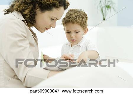Mother and young son reading magazine together View Large Photo Image Stock Photo - Mother and young son reading magazine together. Fotosearch