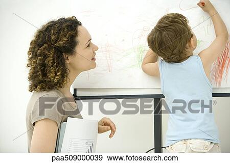 Professional mother holding documents, watching son color with crayon View Large Photo Image Stock Photo - Professional mother holding documents, watching son color with crayon. Fotosearch