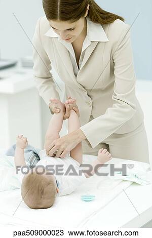 Professional woman changing baby's diaper on desk View Large Photo Image Stock Image - Professional woman changing baby's diaper on desk. Fotosearch
