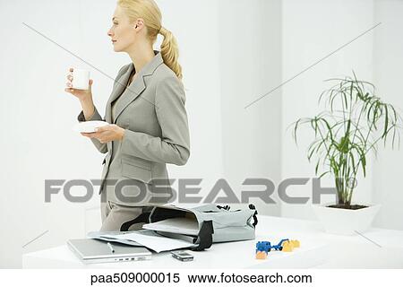 Professional woman holding coffee cup, looking away, bag with laptop and documents on table View Large Photo Image Stock Photography - Professional woman holding coffee cup, looking away, bag with laptop and documents on table. Fotosearch