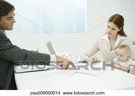 Professional woman in office, holding baby on lap, discussing documents with male colleague View Large Photo Image Picture - Professional woman in office, holding baby on lap, discussing documents with male colleague. Fotosearch