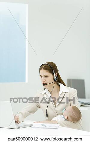 Professional woman in office, holding baby, using headset and laptop computer View Large Photo Image Stock Image - Professional woman in office, holding baby, using headset and laptop computer. Fotosearch