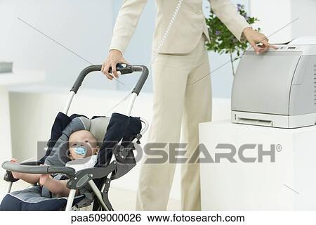 Professional woman in office with baby in stroller, using printer, cropped view View Large Photo Image Stock Photograph - Professional woman in office with baby in stroller, using printer, cropped view. Fotosearch