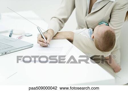 Professional woman signing document at desk, holding sleeping infant, cropped view View Large Photo Image Stock Image - Professional woman signing document at desk, holding sleeping infant, cropped view. Fotosearch