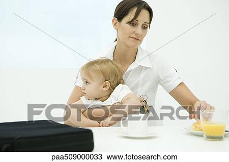 Professional woman sitting at breakfast table, holding toddler and keys View Large Photo Image Stock Image - Professional woman sitting at breakfast table, holding toddler and keys. Fotosearch