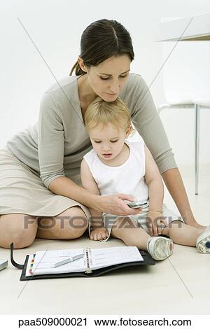 Professional woman sitting on the ground with toddler and agenda, dialing cell phone View Large Photo Image Stock Image - Professional woman sitting on the ground with toddler and agenda, dialing cell phone. Fotosearch