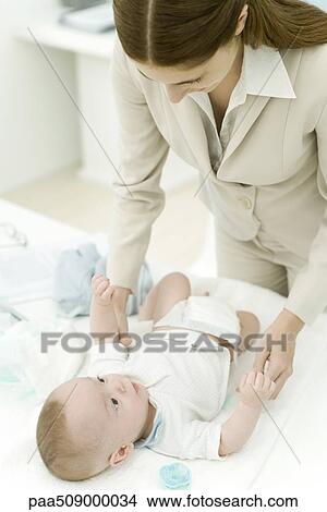 Picture - Young professional mother changing infant's diaper. Fotosearch