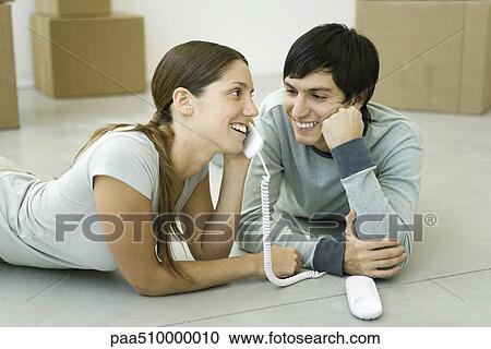 Couple lying on the floor, woman talking on landline phone, boxes in background View Large Photo Image Stock Image - Couple lying on the floor, woman talking on landline phone, boxes in background. Fotosearch