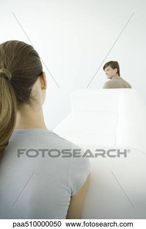 Stock Image - Couple moving sofa together, over the shoulder view. Fotosearch