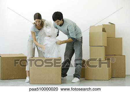 Couple unpacking cardboard boxes together View Large Photo Image Stock Image - Couple unpacking cardboard boxes together. Fotosearch