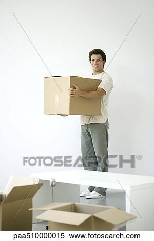 Man holding cardboard box, smiling at camera, opened boxes in foreground View Large Photo Image Stock Photography - Man holding cardboard box, smiling at camera, opened boxes in foreground. Fotosearch
