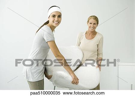 Mother and daughter carrying chair covered in bubble wrap, smiling at camera View Large Photo Image Stock Photography - Mother and daughter carrying chair covered in bubble wrap, smiling at camera. Fotosearch