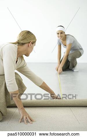 Stock Image - Mother and daughter installing carpet together. Fotosearch