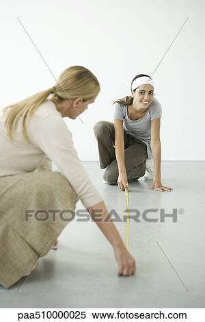 Mother and daughter using measuring tape on the floor View Large Photo Image Stock Photography - Mother and daughter using measuring tape on the floor. Fotosearch
