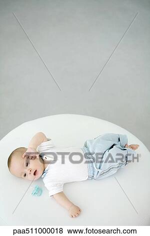 Stock Photo - Baby lying beside pacifier, overhead view. Fotosearch