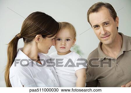 Stock Image - Man beside wife and toddler, smiling at camera. Fotosearch