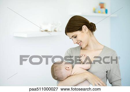 Mother in nursery, smiling down at baby in her arms View Large Photo Image Stock Photo - Mother in nursery, smiling down at baby in her arms. Fotosearch