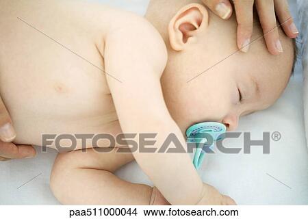 Picture - Mother stroking sleeping baby's head, cropped view. Fotosearch