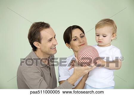Stock Photography - Parents giving toddler a ball. Fotosearch