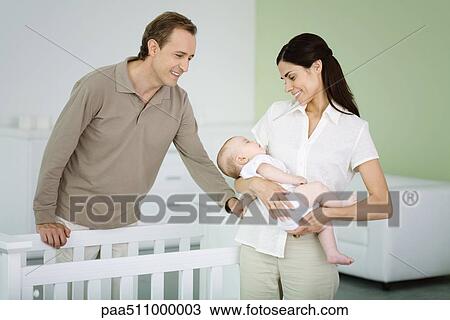 Parents standing in nursery, woman holding sleeping baby View Large Photo Image Stock Image - Parents standing in nursery, woman holding sleeping baby. Fotosearch