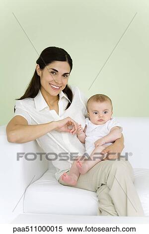 Stock Photography - Woman holding baby on her lap, smiling at camera. Fotosearch