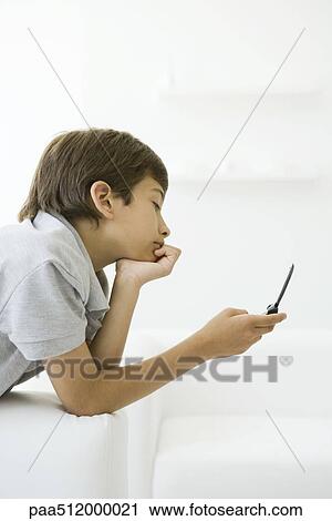 Boy looking at cell phone, hand under chin, side view View Large Photo Image Stock Image - Boy looking at cell phone, hand under chin, side view. Fotosearch