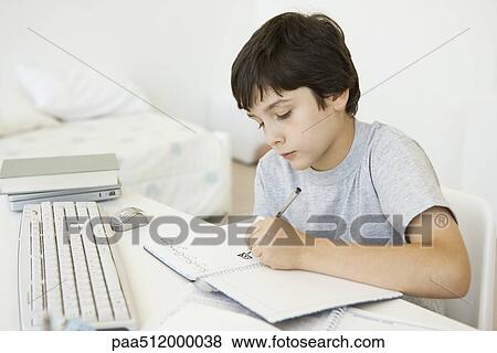 Boy sitting at desk in bedroom, doodling in notebook View Large Photo Image Stock Photo - Boy sitting at desk in bedroom, doodling in notebook. Fotosearch