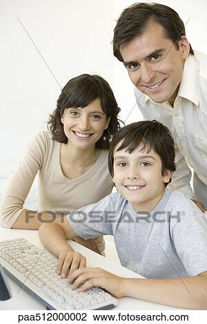 Stock Image - Boy with parents, using keyboard, all smiling at camera. Fotosearch
