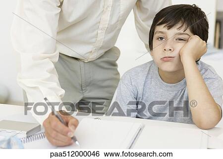 Father helping son with homework, boy holding head and looking away, cropped view View Large Photo Image Stock Photograph - Father helping son with homework, boy holding head and looking away, cropped view. Fotosearch