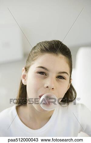 Stock Image - Girl blowing bubble with chewing gum, portrait. Fotosearch
