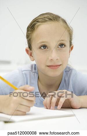 Girl sitting at table, writing in notebook, looking away View Large Photo Image Stock Photo - Girl sitting at table, writing in notebook, looking away. Fotosearch
