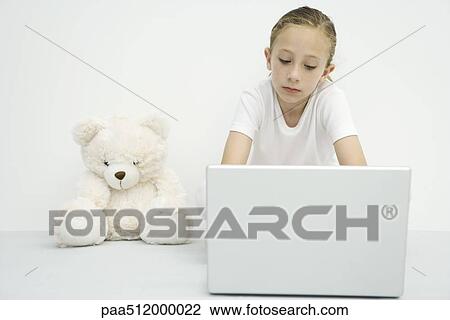 Girl sitting beside teddy bear, using laptop computer View Large Photo Image Stock Image - Girl sitting beside teddy bear, using laptop computer. Fotosearch