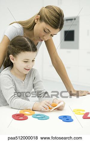 Stock Photo - Mother and daughter looking at cut out numbers together. Fotosearch