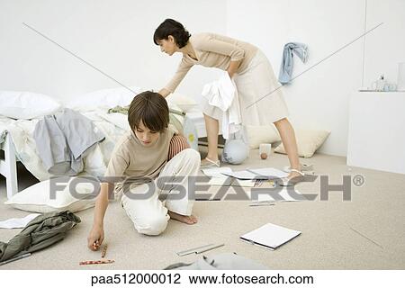 Stock Image - Mother helping boy clean messy room, full length. Fotosearch