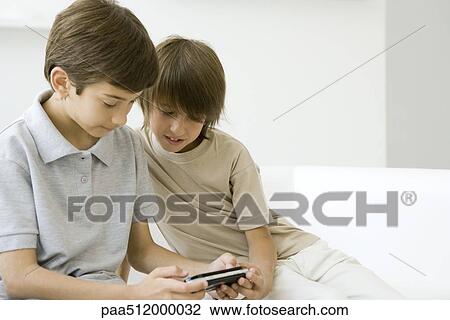 Two boys playing handheld video game together View Large Photo Image Stock Image - Two boys playing handheld video game together. Fotosearch