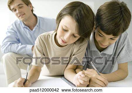 Two boys writing in notebook together, father watching in background View Large Photo Image Stock Image - Two boys writing in notebook together, father watching in background. Fotosearch