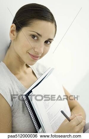 Young woman holding documents and notebook, smiling at camera View Large Photo Image Stock Photograph - Young woman holding documents and notebook, smiling at camera. Fotosearch