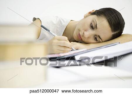 Young woman with stacks of books, writing in notebook, head resting on arms View Large Photo Image Stock Photo - Young woman with stacks of books, writing in notebook, head resting on arms. Fotosearch