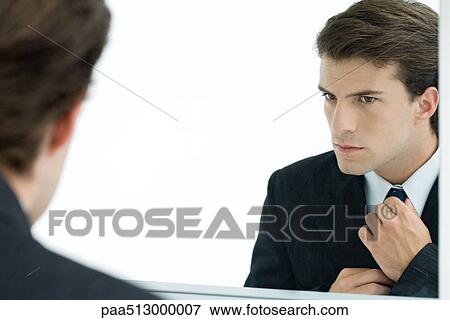 Businessman looking at self in mirror, adjusting tie View Large Photo Image Stock Photo - Businessman looking at self in mirror, adjusting tie. Fotosearch