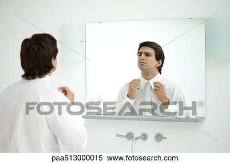 Man wearing button down shirt, adjusting collar in mirror View Large Photo Image Stock Photography - Man wearing button down shirt, adjusting collar in mirror. Fotosearch
