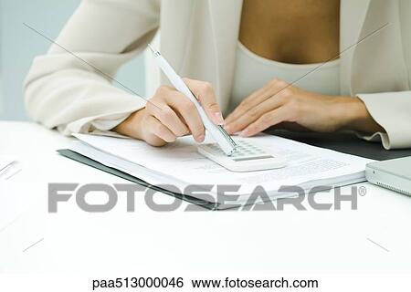 Stock Photograph - Professional woman using calculator, cropped view. Fotosearch
