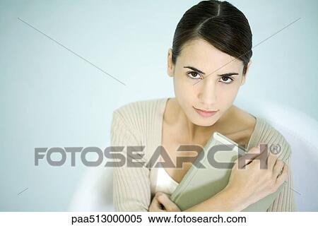 Woman holding book, looking up at camera View Large Photo Image Stock Photography - Woman holding book, looking up at camera. Fotosearch