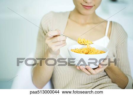 Woman holding bowl of cereal, cropped view View Large Photo Image Picture - Woman holding bowl of cereal, cropped view. Fotosearch