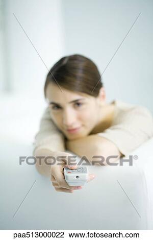Woman pointing remote control at camera, head resting on arms View Large Photo Image Stock Image - Woman pointing remote control at camera, head resting on arms. Fotosearch